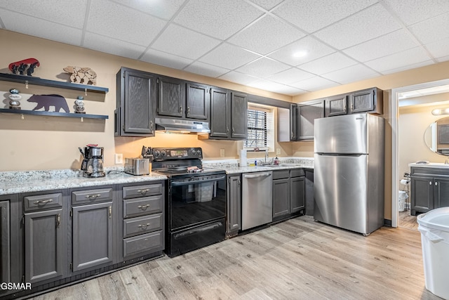 kitchen featuring appliances with stainless steel finishes, a drop ceiling, light stone counters, and light hardwood / wood-style flooring