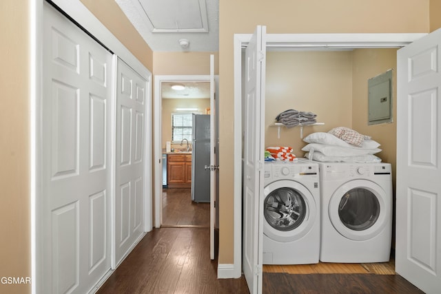 washroom with dark hardwood / wood-style floors, sink, electric panel, and washer and clothes dryer