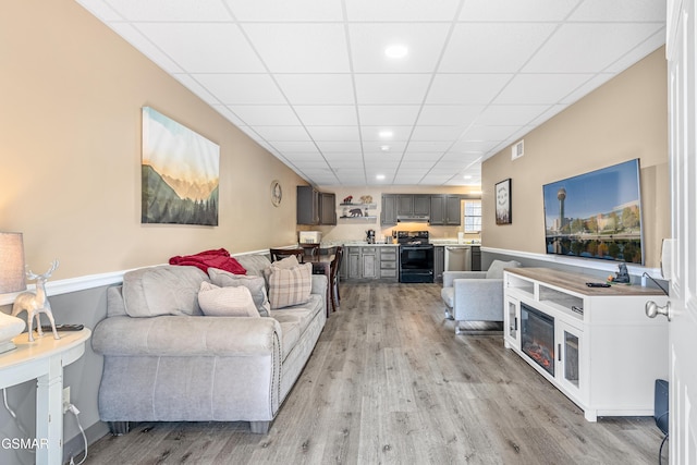 living room with a paneled ceiling and light wood-type flooring