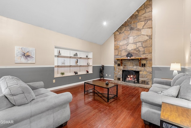 living room with hardwood / wood-style flooring, a stone fireplace, and high vaulted ceiling