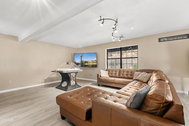 living room with beamed ceiling, light hardwood / wood-style flooring, and a textured ceiling