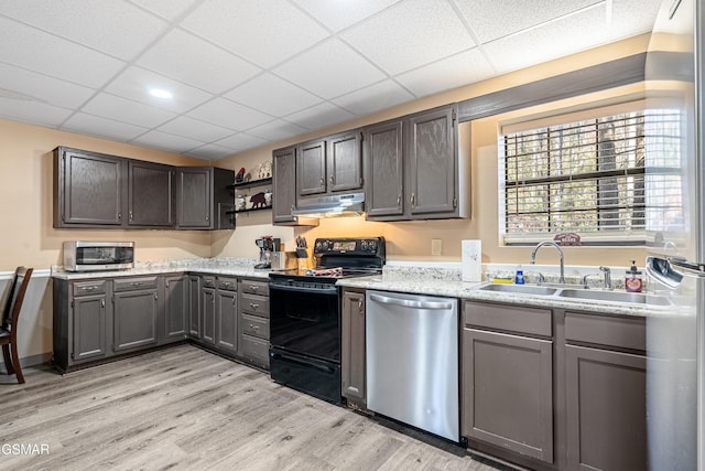 kitchen featuring appliances with stainless steel finishes, sink, a drop ceiling, and light wood-type flooring