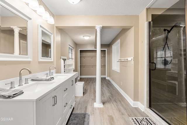 bathroom with walk in shower, a textured ceiling, vanity, hardwood / wood-style flooring, and decorative columns