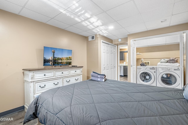 bedroom featuring connected bathroom, a paneled ceiling, separate washer and dryer, a closet, and hardwood / wood-style floors