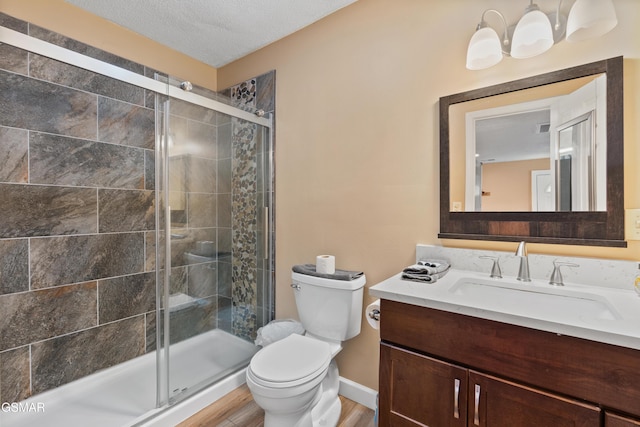 bathroom with hardwood / wood-style floors, vanity, a textured ceiling, a shower with shower door, and toilet