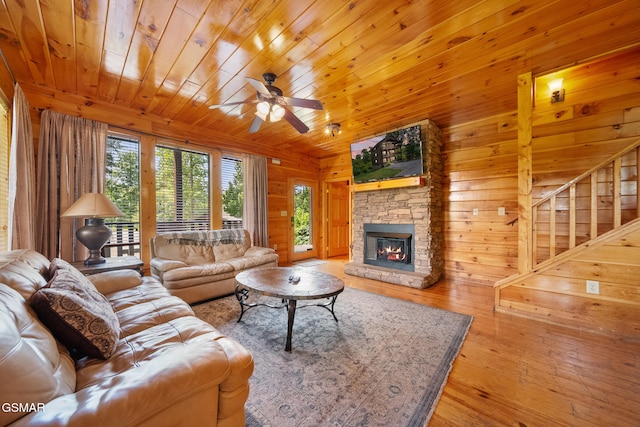 368 Oak Lake Dr, Sevierville, TN 37876 - living area featuring wooden walls, a stone fireplace, a ceiling fan, wood-type flooring, and stairs