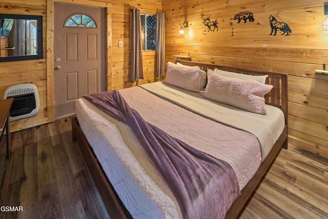 bedroom featuring wood-type flooring, heating unit, and wooden walls