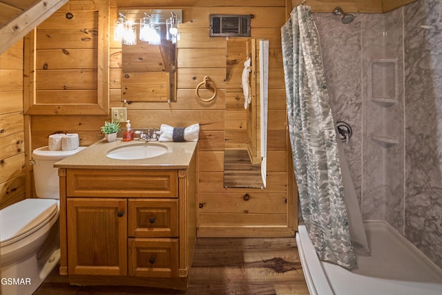 bathroom featuring walk in shower, vanity, wooden walls, hardwood / wood-style floors, and toilet