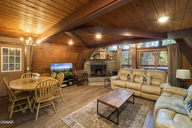 living room featuring wood walls, an inviting chandelier, a stone fireplace, hardwood / wood-style flooring, and beamed ceiling