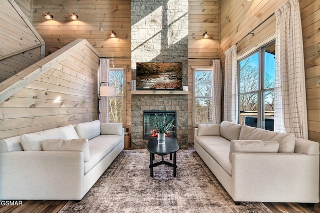 living room featuring wood walls, a fireplace, and high vaulted ceiling