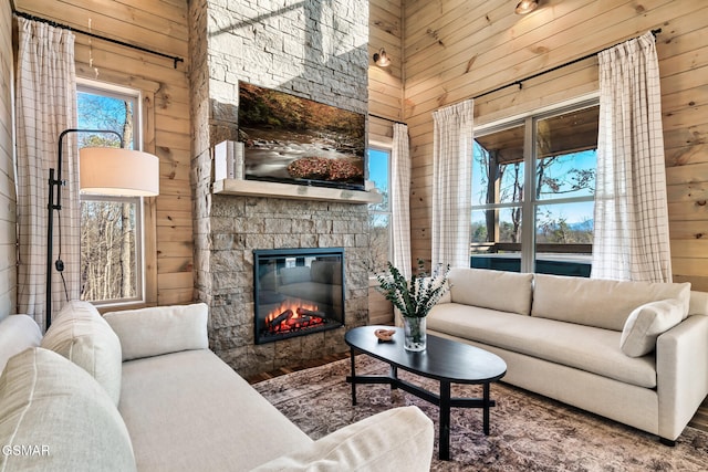 living room with a stone fireplace and wooden walls