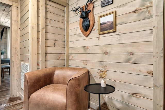 living area with wood-type flooring and wood walls