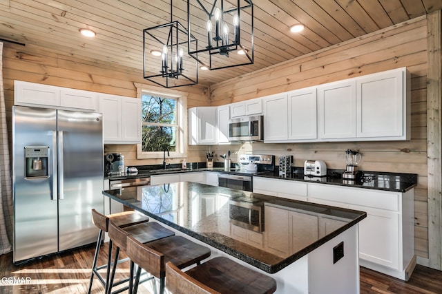 kitchen featuring decorative light fixtures, stainless steel appliances, a kitchen island, and white cabinetry