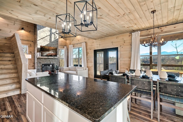 kitchen with wood ceiling, wood walls, white cabinets, and hanging light fixtures