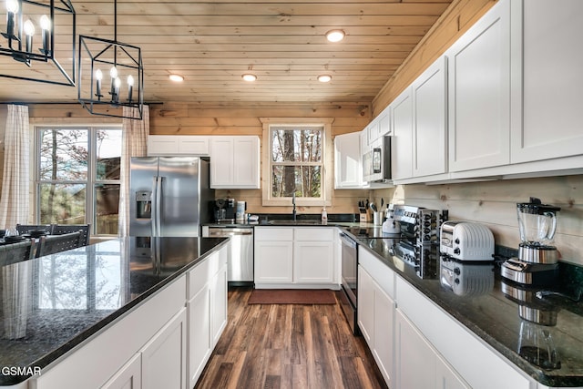 kitchen with white cabinetry, stainless steel appliances, an inviting chandelier, decorative light fixtures, and wood ceiling