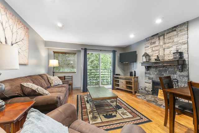 living room with light wood-type flooring and a stone fireplace