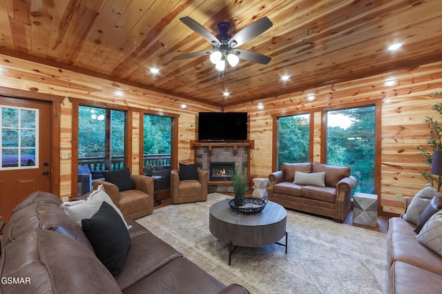 living room with ceiling fan, a healthy amount of sunlight, wooden ceiling, a fireplace, and wood walls