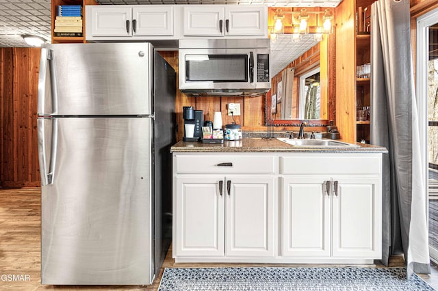 3115 E E Pkwy, Gatlinburg, TN 37738 - kitchen featuring wooden walls, dark stone counters, stainless steel appliances, white cabinetry, and a sink