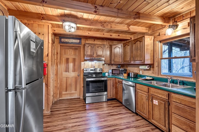 kitchen with wood ceiling, stainless steel appliances, a sink, and beamed ceiling