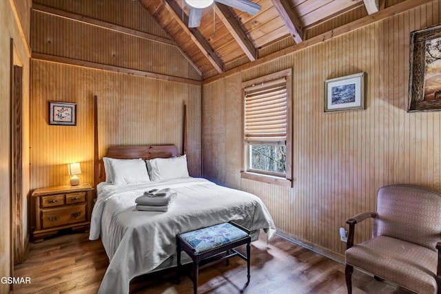 bedroom with lofted ceiling with beams, wood finished floors, wood ceiling, and wooden walls