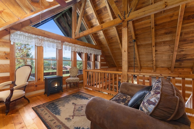 sitting room featuring a wood stove, lofted ceiling with beams, wooden walls, wood-type flooring, and wood ceiling