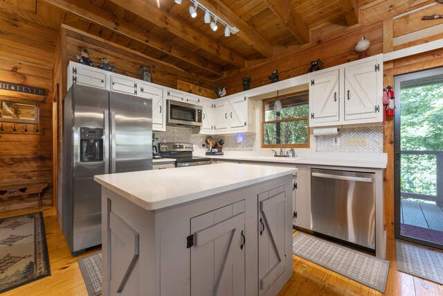 kitchen with white cabinets, a center island, a healthy amount of sunlight, and stainless steel appliances