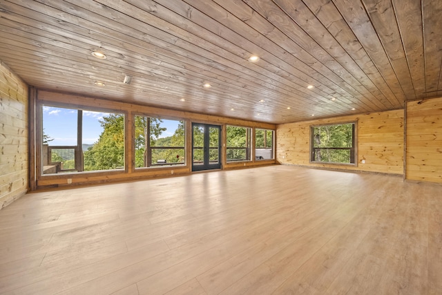 unfurnished living room featuring wood walls, light hardwood / wood-style flooring, and wood ceiling