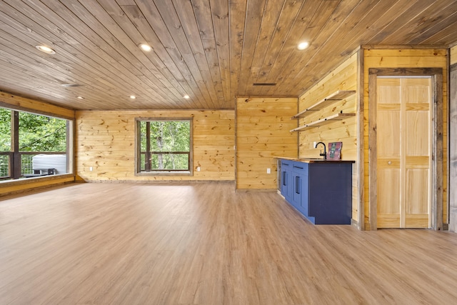 unfurnished living room featuring wooden ceiling, sink, wooden walls, and light hardwood / wood-style flooring