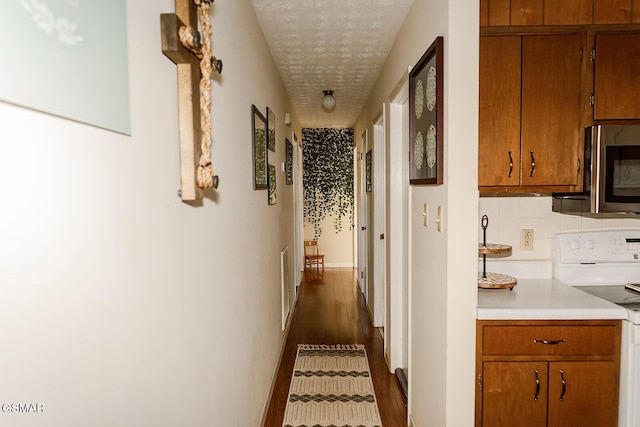 corridor with a textured ceiling and dark wood-type flooring