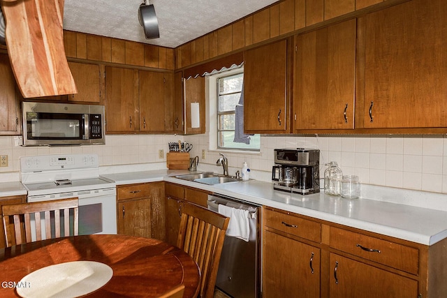 kitchen featuring a textured ceiling, stainless steel appliances, tasteful backsplash, and sink