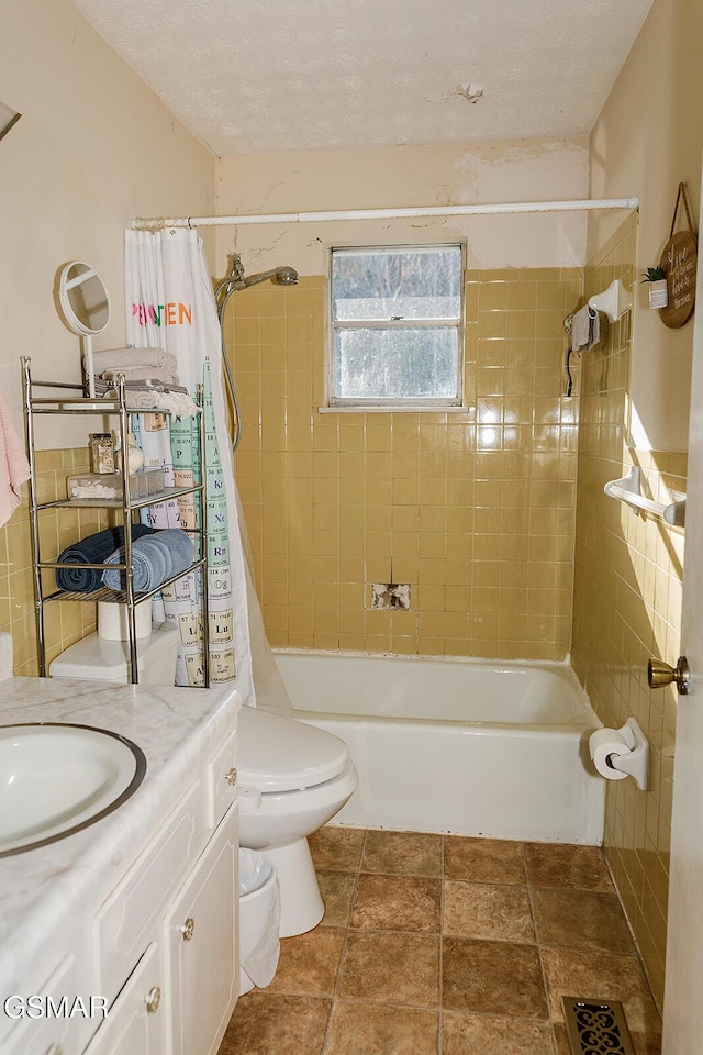 full bathroom featuring a textured ceiling, vanity, toilet, and tiled shower / bath combo