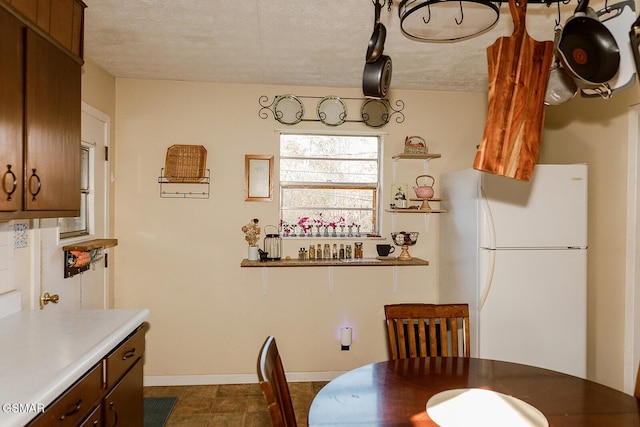 kitchen with dark brown cabinetry, a textured ceiling, and white refrigerator