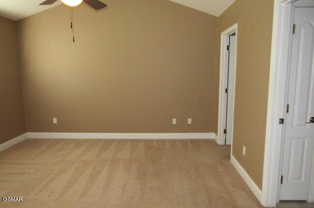 empty room with light colored carpet, ceiling fan, and lofted ceiling