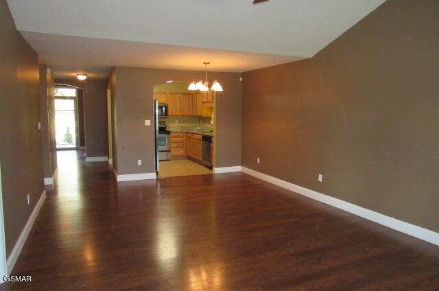 unfurnished living room featuring dark hardwood / wood-style floors and a notable chandelier