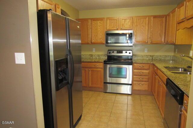 kitchen with light stone counters, sink, light tile patterned flooring, and appliances with stainless steel finishes