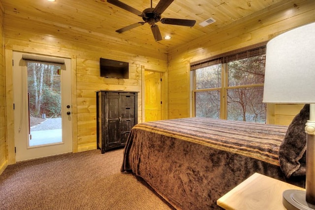 bedroom with carpet flooring, access to exterior, ceiling fan, and wood walls