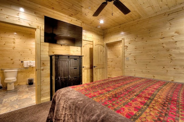 carpeted bedroom with ceiling fan, wood walls, wood ceiling, and ensuite bath