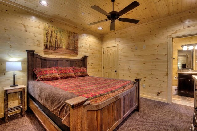 bedroom featuring ceiling fan, wooden ceiling, ensuite bathroom, wood walls, and carpet