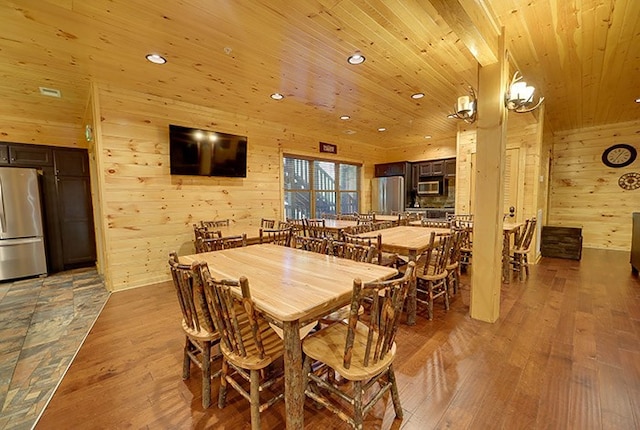 dining space with hardwood / wood-style flooring, wood walls, and wood ceiling