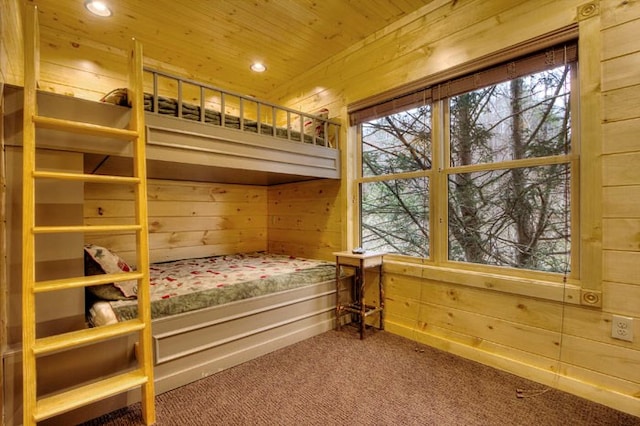 carpeted bedroom featuring wooden ceiling and wooden walls