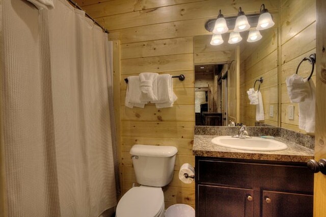 bathroom featuring vanity, toilet, wood ceiling, and wooden walls