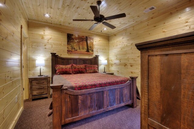 bedroom featuring ceiling fan, wood ceiling, wood walls, and dark carpet