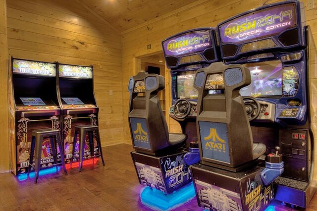 recreation room with wood walls, hardwood / wood-style floors, and lofted ceiling