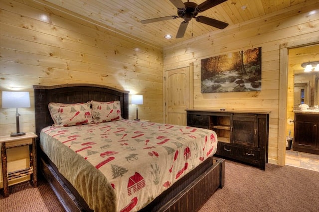 carpeted bedroom with ceiling fan, wood ceiling, wooden walls, and ensuite bath
