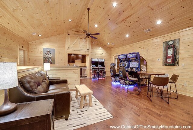 living room featuring wooden ceiling, high vaulted ceiling, wooden walls, hardwood / wood-style flooring, and ceiling fan