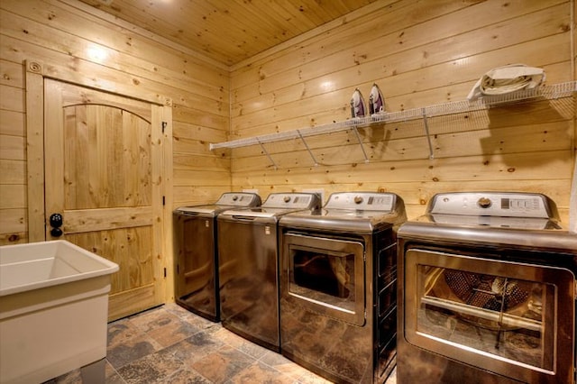 clothes washing area featuring washer and dryer, wooden ceiling, sink, and wooden walls