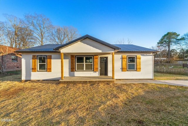 view of front of home featuring metal roof, a porch, a standing seam roof, and fence