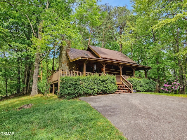 view of front of property featuring covered porch, metal roof, a front lawn, and a chimney