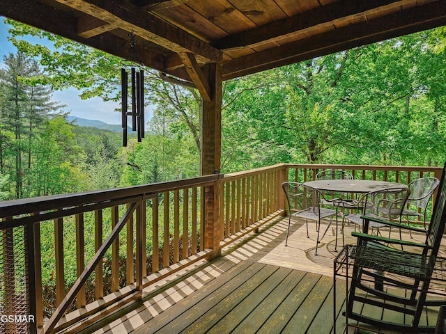 deck with a wooded view and outdoor dining space