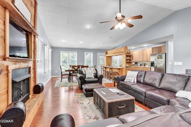 living area featuring ceiling fan, a large fireplace, light wood-style flooring, recessed lighting, and vaulted ceiling